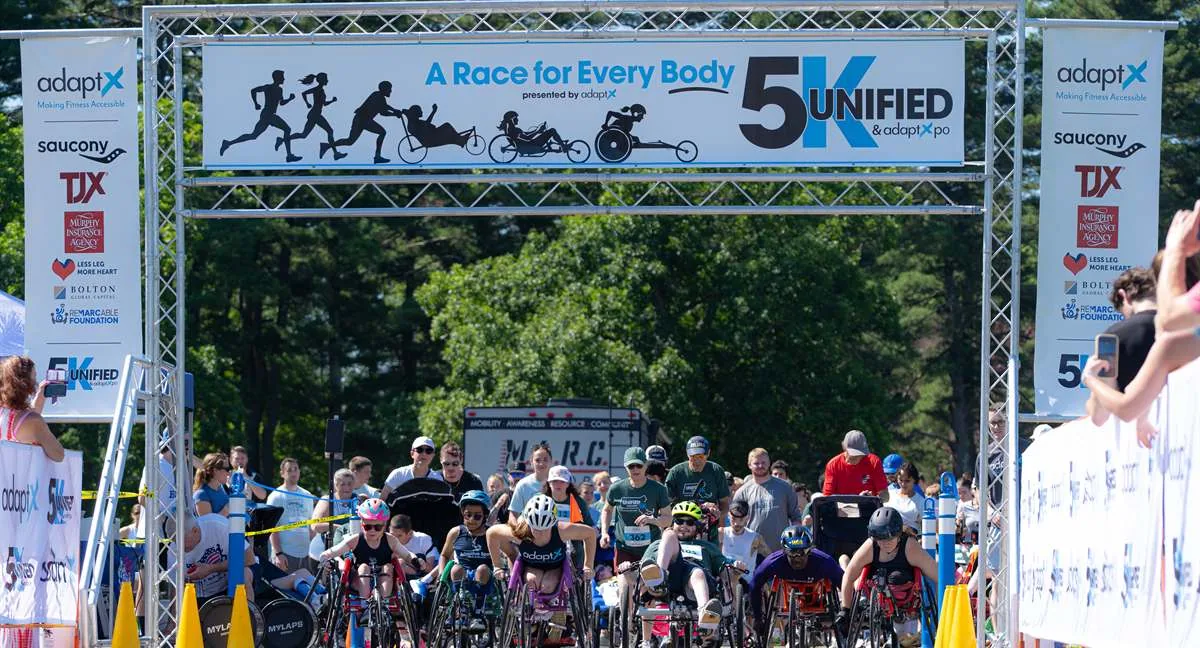 Wheelchair racers and runners setting off together under the Unified 5K start arch